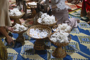 Peaceful Asian ceremony, cultural tradition of handmade textile craft. Woven baskets on decorative mat hold raw silk fiber or cotton, showing serene and focused process