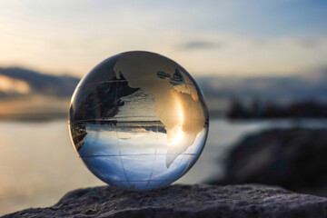 Crystal globe on ocean background with sunrise and dusk. Earth concept. Crystal globe in the...