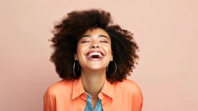 A joyful woman with curly hair laughs openly. Captured from a front-facing angle, the vibrant portrait is ideal for a video thumbnail or lifestyle content.
