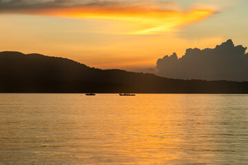 Obraz premium glowing horizon over calm backwater with boats at evening sunset