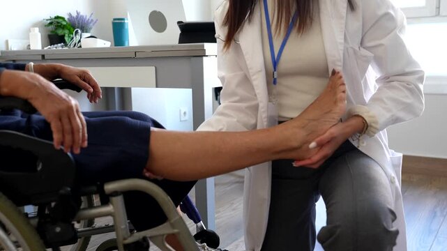 Professional female physiotherapist examining the leg and foot of an elderly woman sitting in a wheelchair, providing specialized rehabilitation and medical assistance in a modern clinic
