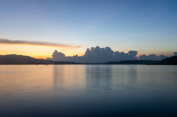 serene coastal scene with mountain horizon and clouds