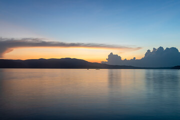 serene coastal scene with mountain horizon and clouds