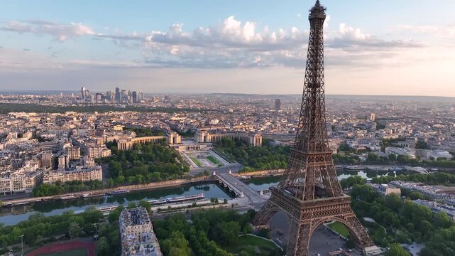 Aerial drone view of the streets of Paris, France, overlooking the famous Eiffel Tower and Champ de Mars at sunrise or sunset. Sun rays pass through the tower. Cinematic 4k. Europe from above
