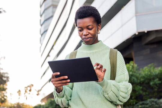 portrait of a young african american woman using a tablet in front of a building, concept of youth and student lifestyle, copy space for text