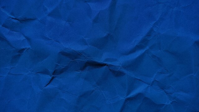 Wrinkled dark blue paper background with soft wave texture. Crumpled blue vintage paper surface texture for background. Wrinkled paper background with copy space for text.