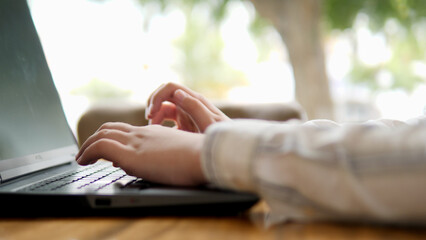 A Person Actively Typing on a Laptop while Enjoying the Benefits of Natural Light
