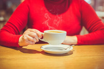 A girl drinks coffee at a table in a cafe
