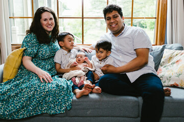 Mom, Dad and children of latino descent at home together on couch
