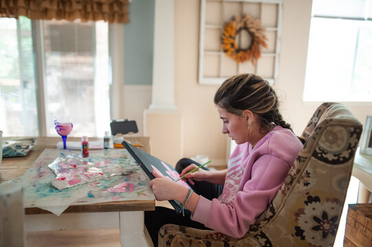 Young woman creating colorful artwork while sitting at her home table