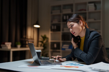 Woman working late on phone and laptop