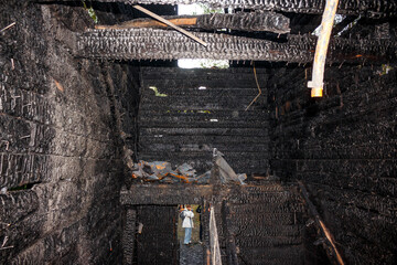Inside a wooden home after a devastating fire. Charred timbers and walls reveal the destructive...