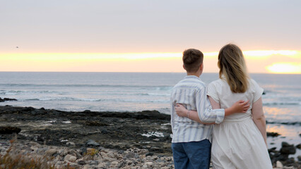 Fototapeta premium A couple delicately embracing each other at sunset on the beautiful beach by the ocean,