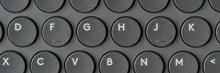 Close-up of circular black keyboard keys with white letters in a retro design.