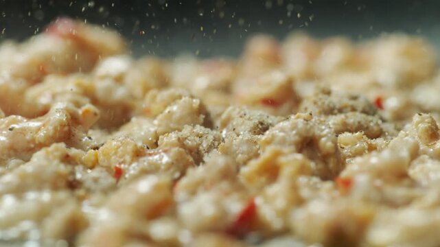 Close up seasoning powder sprinkled over sizzling minced pork for Pad Krapow, Thai street food 4k slow motion