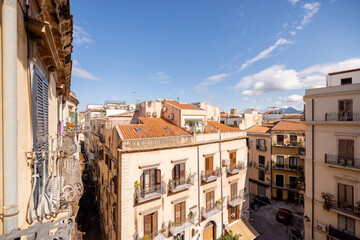 Sunny view of Palermo old town with warm terracotta rooftops, historic balconies, and blue Sicilian sky. Mediterranean charm and timeless Italian architecture