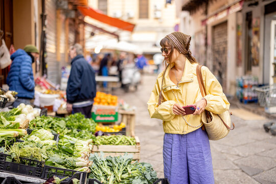 Woman browsing fresh vegetables at a traditional Sicilian street market in Palermo. Authentic Mediterranean lifestyle and local food culture
