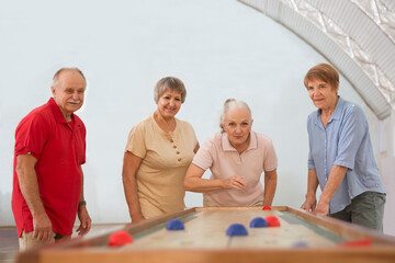 senior group Playing the board game of shuffleboard.  Kidult gaming in the gym. Active retirement...