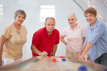 senior group Playing the board game of shuffleboard.  Kidult gaming in the gym. Active retirement...