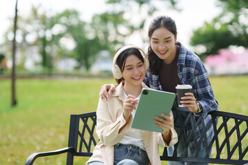 Friends sharing digital tablet in green park