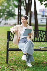 Young woman enjoying music, using digital tablet in park