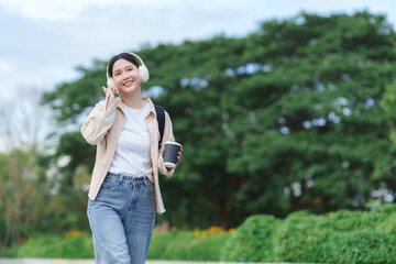 Young woman walking, listening music, holding coffee cup