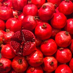 Vivid close-up of ripe, red fruit with one halved, revealing jewel-like seeds
