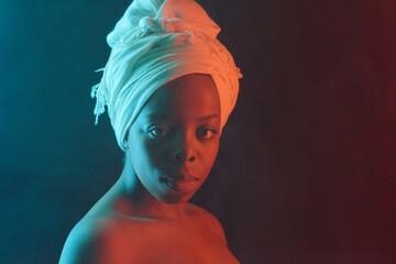 Close-up portrait of young beautiful African American woman in white turban with bare shoulders...