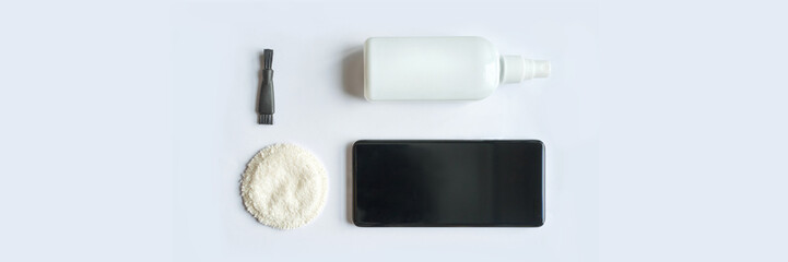 Smartphone cleaning kit: black screen cloth brush bottle on white surface for device maintenance.