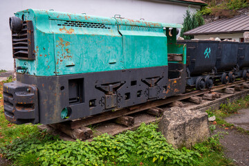 Old mining locomotive with ore wagons on display, once used for local ore transport in a historical mining area.