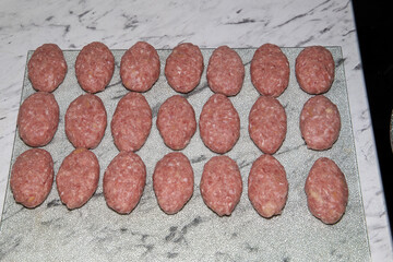 Freshly prepared beef and pork patties lined up in the kitchen. The patty-making process.