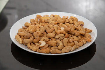 Cashews on a plate, top view. Loose cashews, close-up. Healthy eating concept.