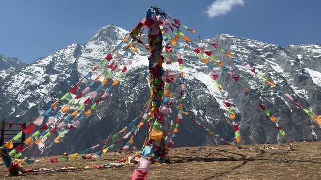 Colorful prayer flags tied to a tall pole near Muktinath in Mustang, Nepal, with snow-covered Himalayan peaks in the background symbolizing peace, spirituality, and mountain devotion.