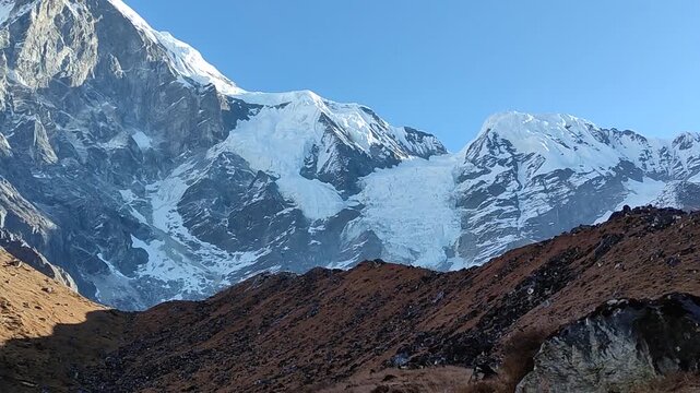 Majestic mountain landscape near Tilicho Lake in the Annapurna region, Nepal, with snow-covered peaks, rocky slopes, and glacier formations under clear blue sky in pristine high-altitude terrain