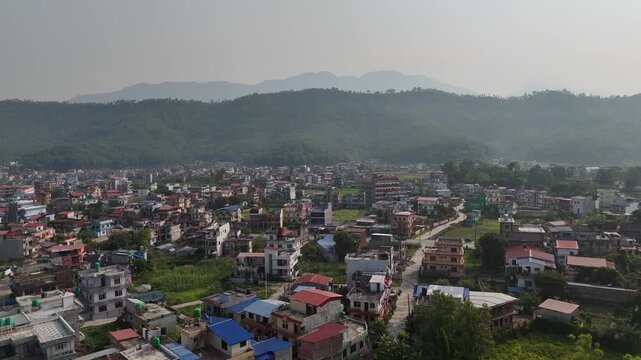 Drone view of Tansen town in Palpa District showing colorful houses, winding streets, and lush surrounding hills under a hazy sky, highlighting charm of a peaceful hill settlement.
