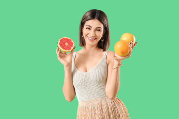 Beautiful young woman with grapefruits on green background