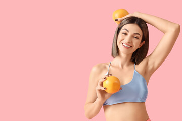 Young woman with grapefruits on pink background