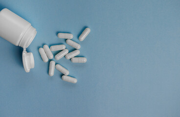 Healthcare, pharmacy and treatment concept. Close-up of scattered capsules and white pharmacy bottle.
