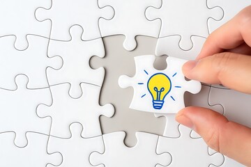 Business hand placing puzzle piece with light bulb representing idea creativity innovation solution thinking concept teamwork achievement strategy creative problem solving and development strategy 