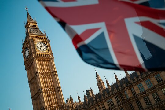 Iconic big ben clock tower and the union jack flag waving against a clear blue sky in london england