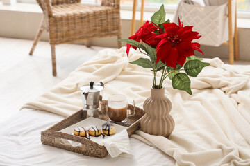 Breakfast with cottage cheese pancakes and Christmas plant poinsettia on bed in room