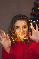 young pretty woman holding a garland against the background of a New Year tree