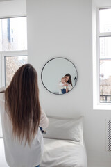 young woman holding baby in her arms and looking in the mirror