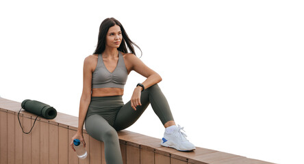 fit young woman sits by the waterfront, opening a water bottle after a workout against transparent background
