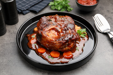 Tasty beef ossobuco with carrot, parsley and sauce on grey textured table, closeup