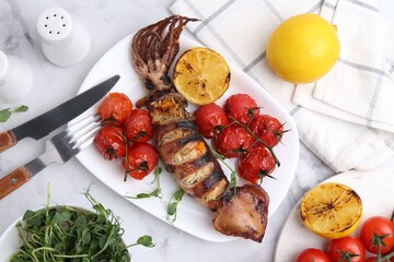 Tasty stuffed squid, microgreens, lemon and tomatoes on white marble table, flat lay