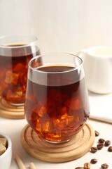 Tasty iced coffee and beans on white table, closeup