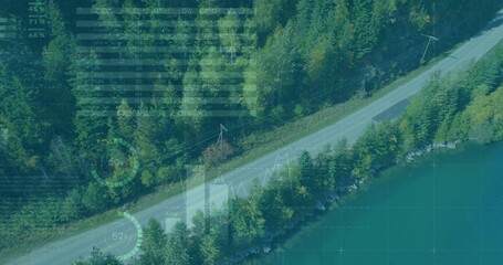 Showing two-lane road through forest beside turquoise lake from aerial vantage power lines, HUD
