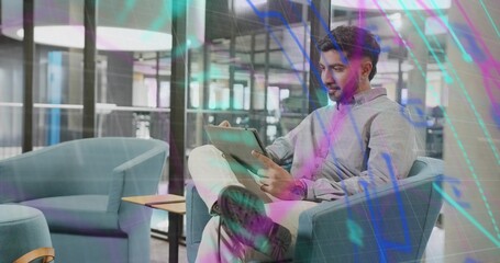 Sitting office professional in teal armchair wearing grey shirt in office lounge, with tablet