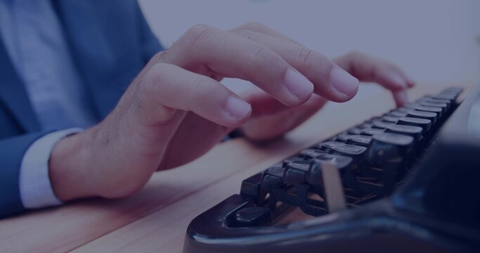 Male hands wearing business attire typing on black keyboard at office light wood desk surface